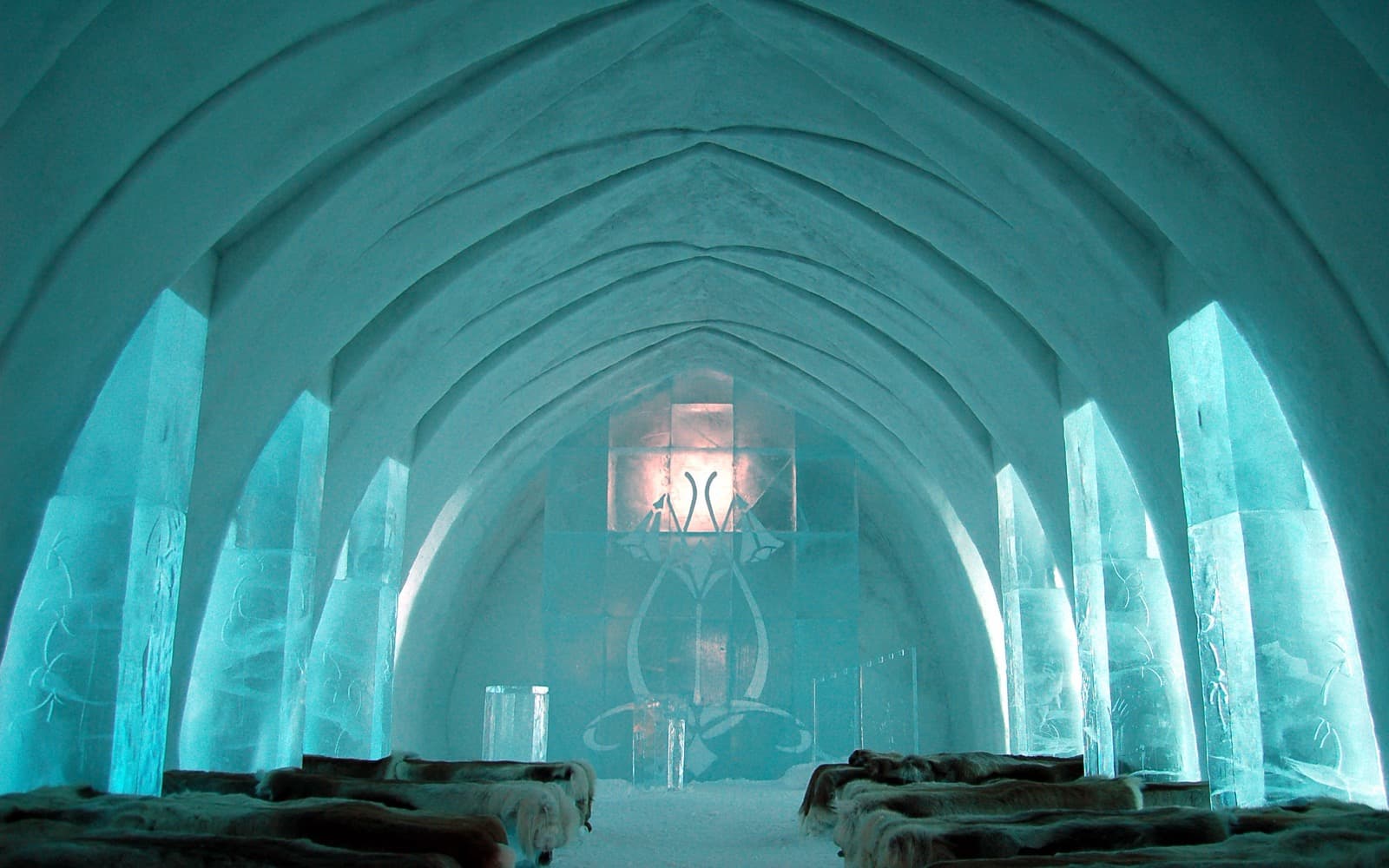 Iskyrkan i Jukkasjärvi med pelare av is, välvt snötak och bänkar täckta med renskinn.