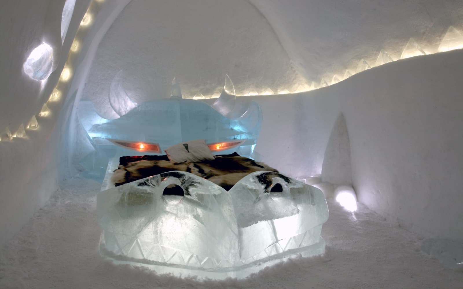 Ett hotellrum av snö och is där sängen är formad som en drake, med renskinn på madrassen.