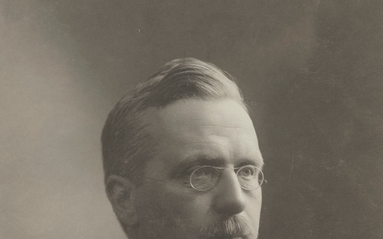 Svartvitt porträtt av Fridtjuv Berg med glasögon och mustasch.