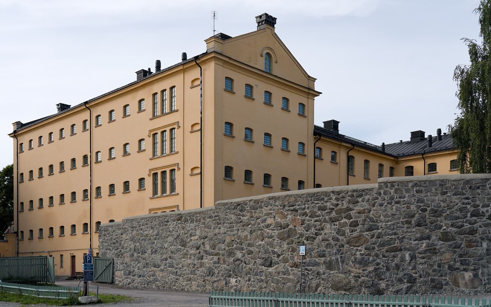 En lång gul fängelsebyggnad med gröna fönsterluckor på Långholmen