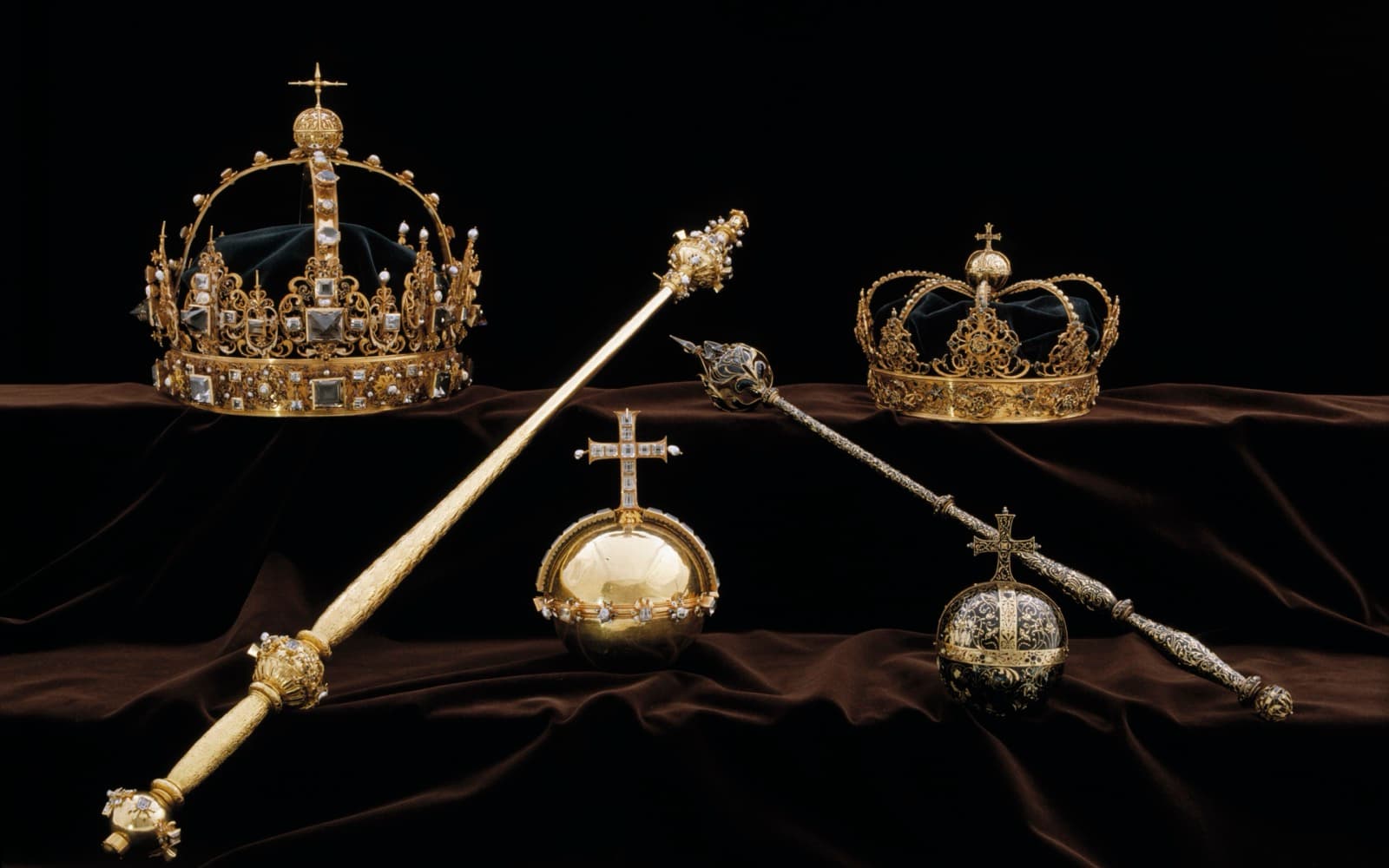 Två guldkronor, två riksäpplen och två spiror på mörk sammet, Karl IX:s och drottning Kristina den äldres begravningsregalier.
