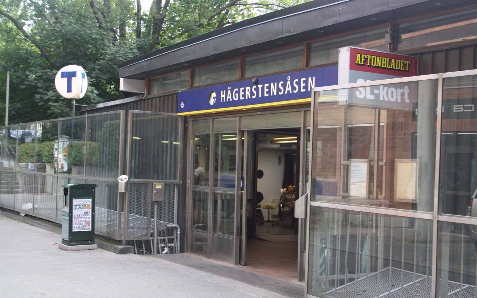 Entrén till tunnelbanestationen Hägerstensåsen med blå skylt och glasväggar