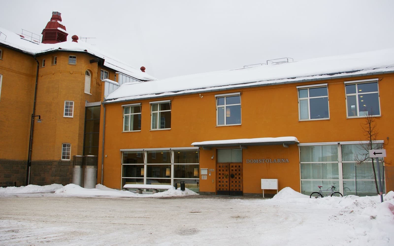 En orange tegelbyggnad med skylten Domstolarna ovanför entrén, med snö på marken