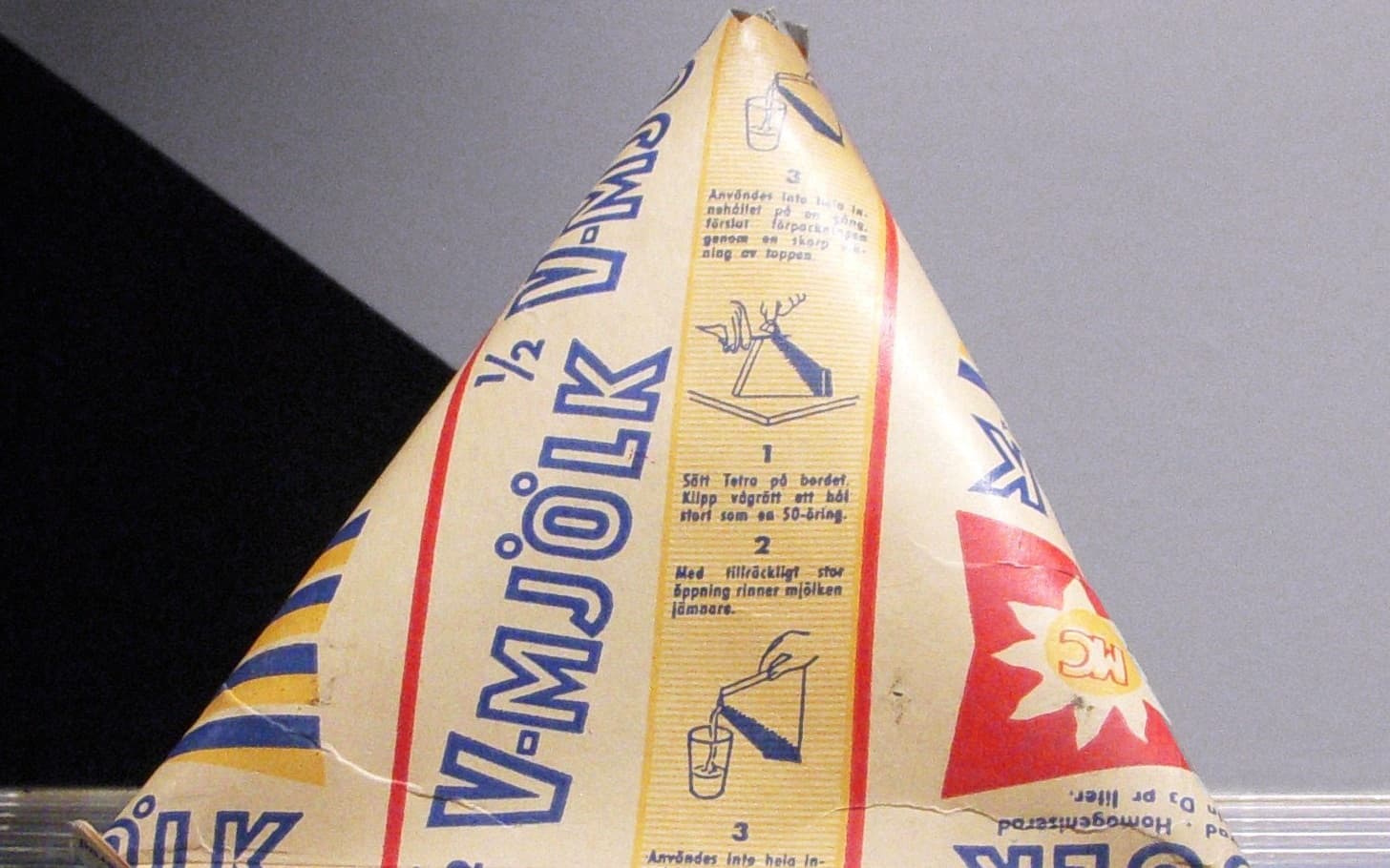 Ett gammalt tetraederformat mjölkpaket med texten V-mjölk och instruktioner för att klippa upp det